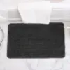 Schwarze Anti-Rutsch-Badematte im Badezimmer auf Marmorfliesen.