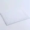 Weisse Anti-Rutsch-Badematte aus Baumwolle mit griechischem Muster, ideal für Badezimmer.