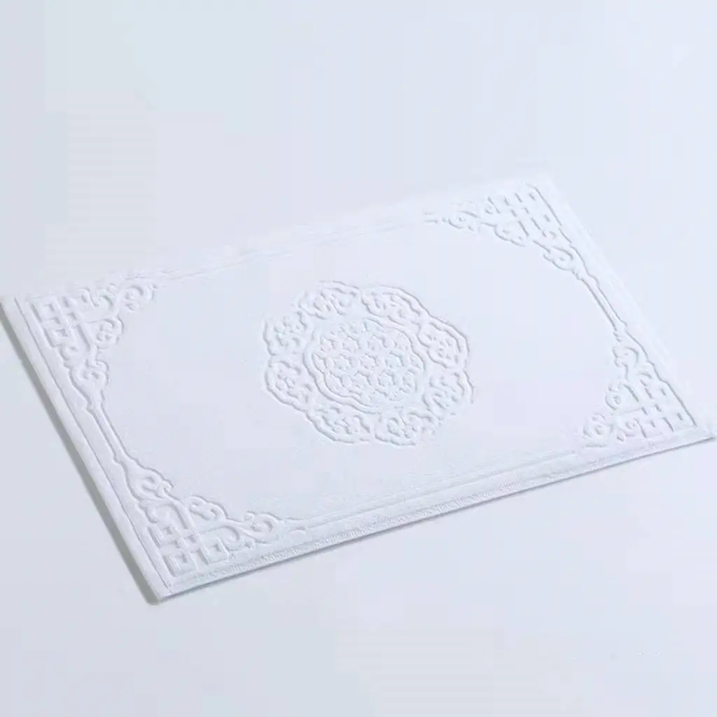Weisse Badematte aus Baumwolle mit filigranem Ornamentmuster, ideal für Badezimmer.