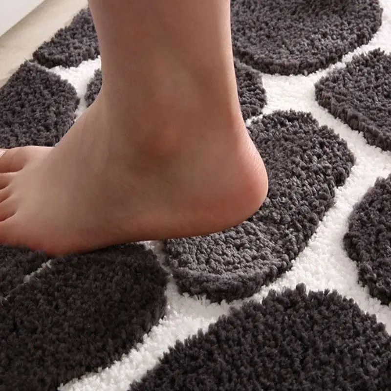 Fuss auf grauer Badematte mit Memory Foam, runden Mustern, weich und absorbierend.