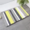 Runde Badematte mit gelb-grauen Streifen, ideal für Badezimmer und Dusche.