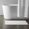 Weisser Badezimmerteppich aus Baumwolle mit Bordüre, ideal für moderne Badezimmer.