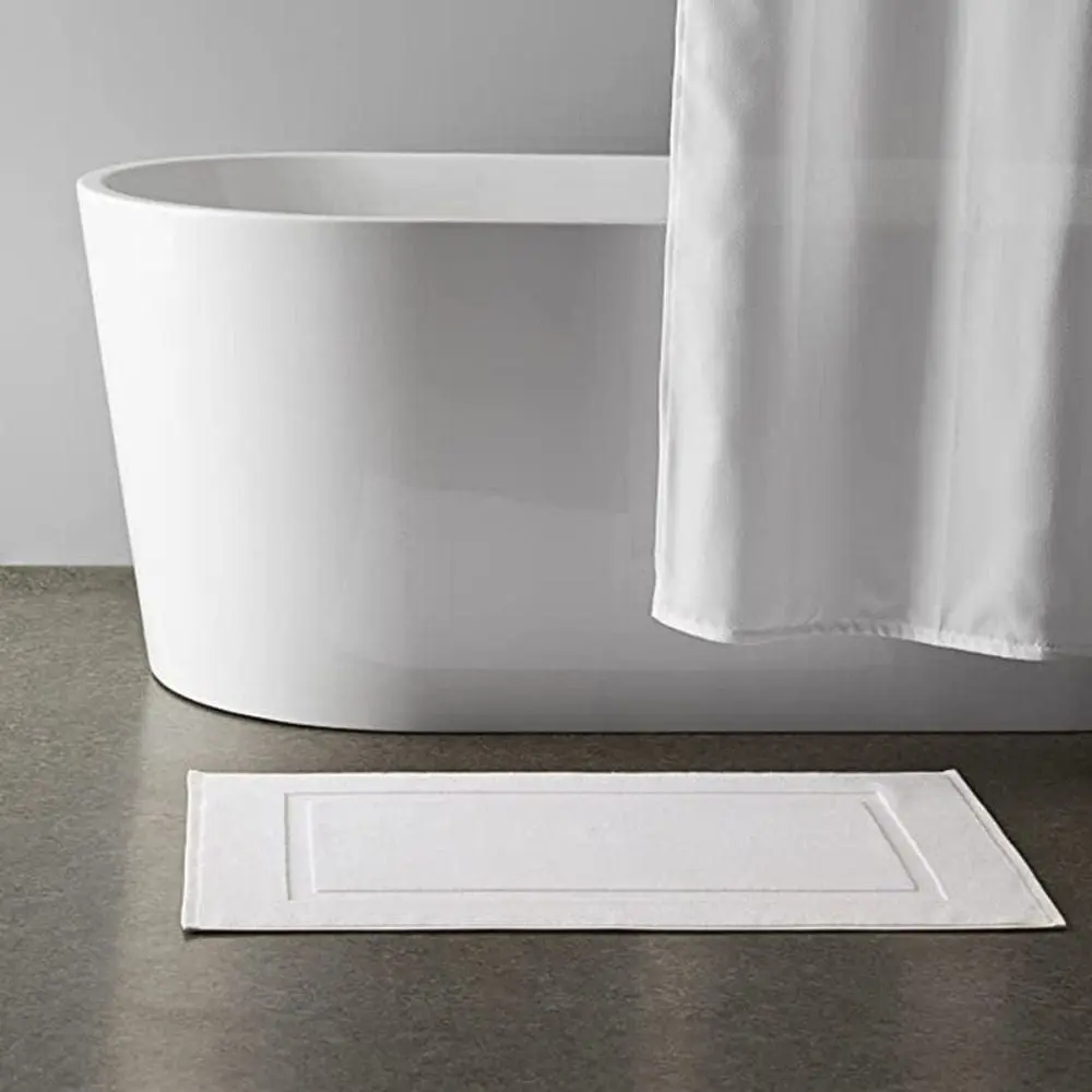 Weisser Badezimmerteppich aus Baumwolle mit Bordüre, ideal für moderne Badezimmer.