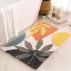 Skandinavischer Badezimmerteppich mit Blattmuster in Orange, Gelb und Grau, ideal für moderne Badezimmer.