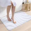 Weisser Badteppich mit Wellenmuster, weiches Material, ideal für Badezimmer.