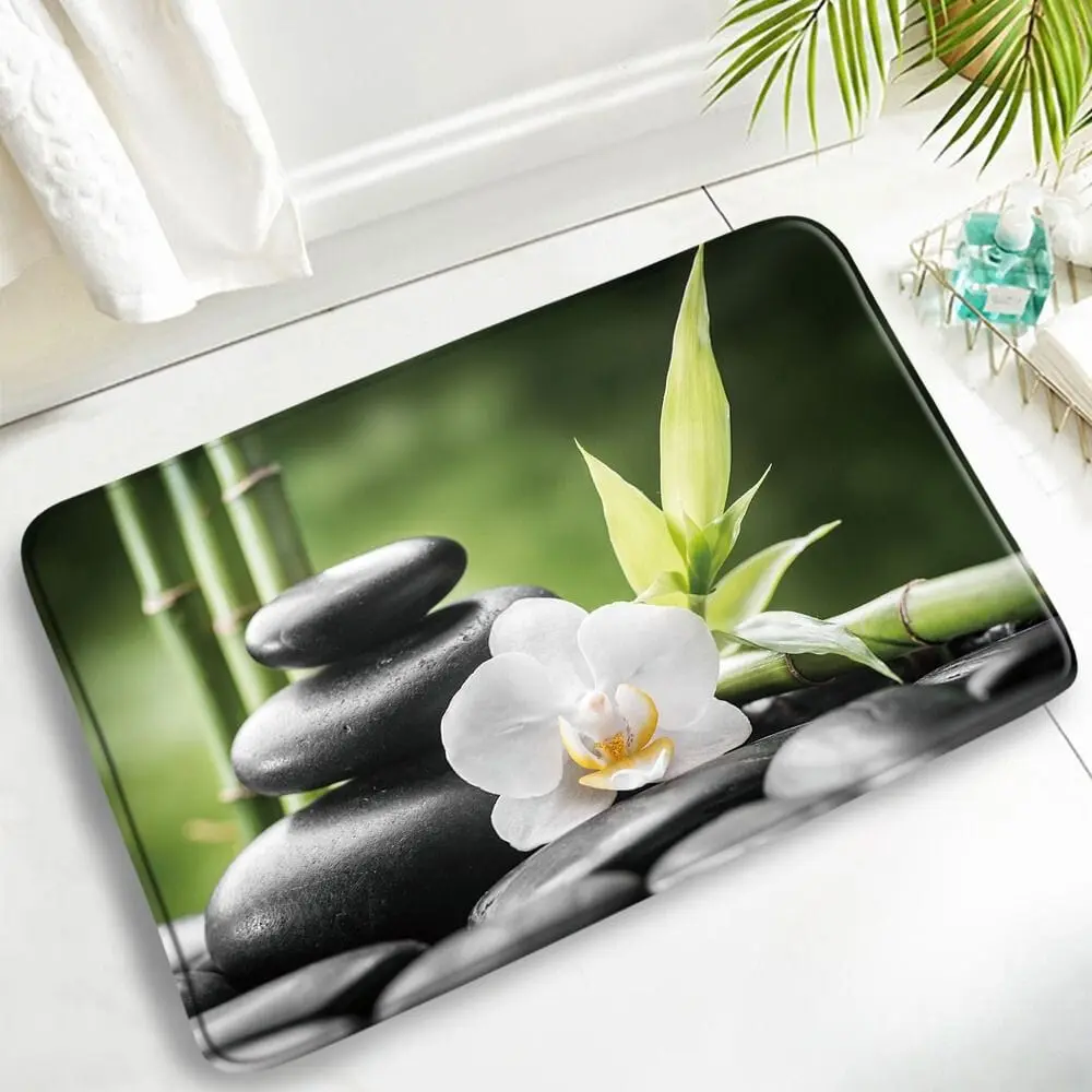 Badteppich mit Naturmotiv: weiße Orchidee, schwarze Steine und Bambus, ideal für Badezimmer.