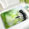 Badteppich mit Zen-Motiv, schwarze Steine, grüne Bambusblätter und weiße Blume, ideal für Badezimmer.