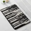 Schwarz-Weiss gestreifter Badteppich mit flauschigem Hochflor, ideal für Badezimmer.