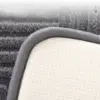 Badteppich Design mit grauem Fleece-Bezug und weisser, strukturiertem Unterseite.