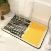 Modern gestreifter Badteppich mit gelbem Feld, ideal für Badezimmer.