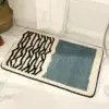 Modern gestreifter Badteppich mit blauem Feld, ideal für Badezimmer.