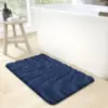 Rutschfester Badteppich in Dunkelblau mit Wellenmuster vor Badewanne.