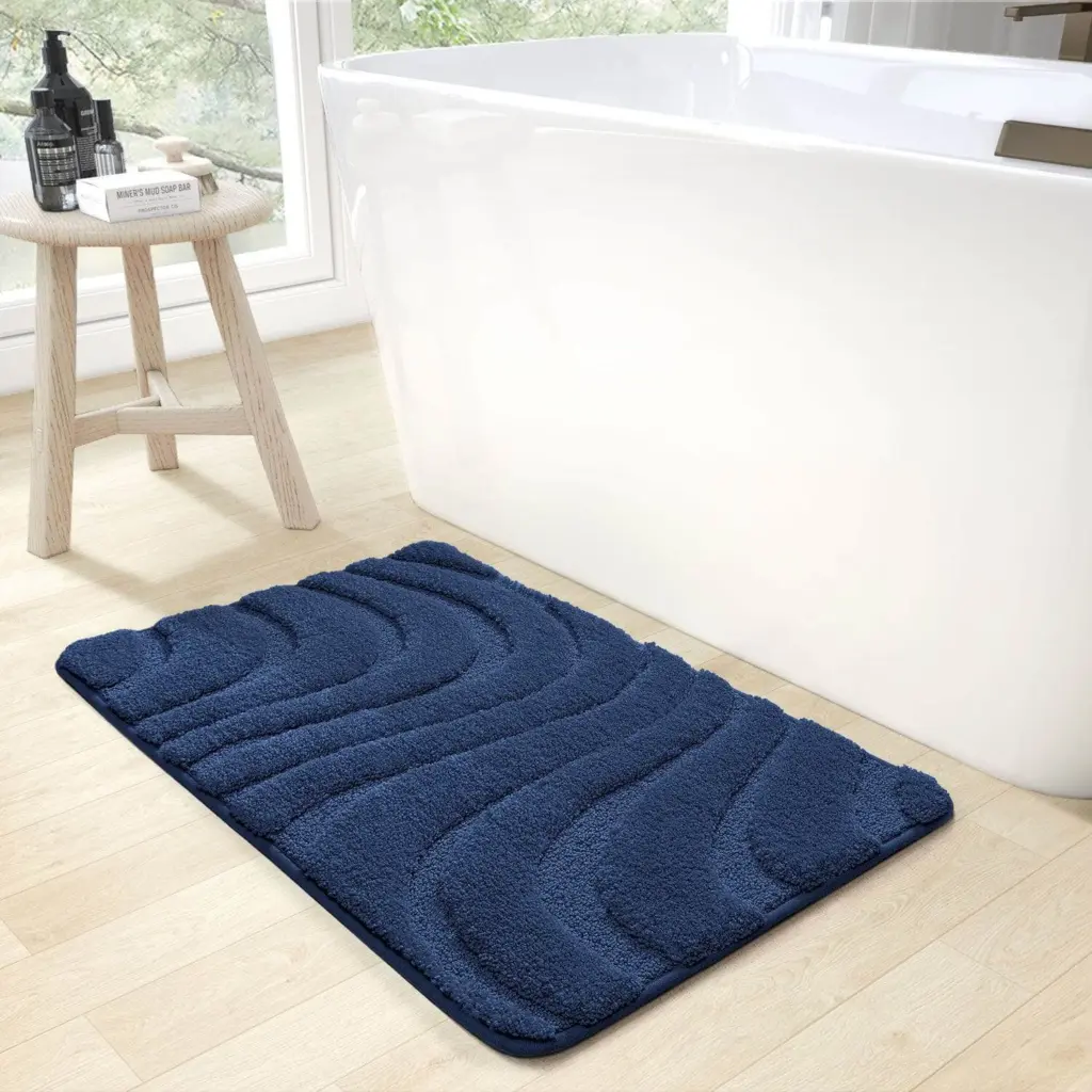 Rutschfester Badteppich in Dunkelblau mit Wellenmuster vor Badewanne.