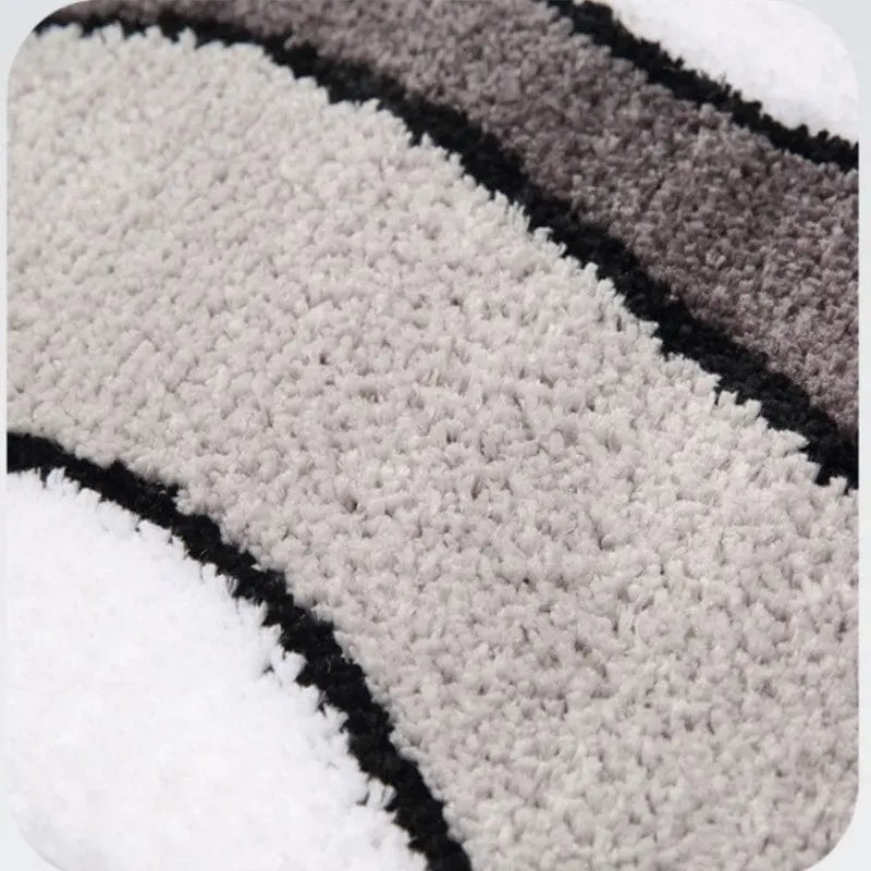 Weisser Badteppich mit grauen und schwarzen Streifen, weicher Faserstruktur, ideal für Badezimmer.