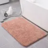 Rosafarbener Badteppich mit weicher Textur vor der Badewanne.