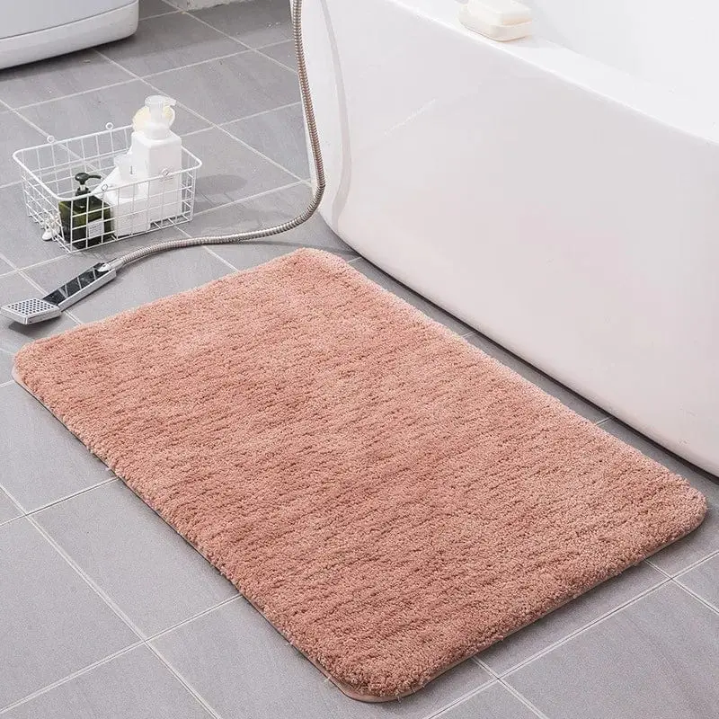 Rosafarbener Badteppich mit weicher Textur vor der Badewanne.