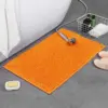 Orange Chenille Badteppich mit weicher Textur im Badezimmer.