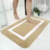Grosse Badematte beige mit weißem Rand, weiches Material, ideal für Badezimmer.