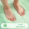 Grüne Badematte mit weichem Flor, absorbierend für nasse Füsse im Badezimmer.