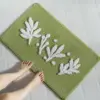 Olivgrüne Badematte mit weißen Blattmotiven, weiches Material, ideal für Badezimmer.