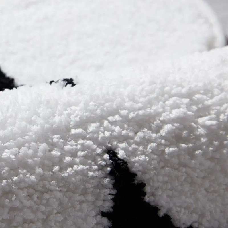Schwarz-Weisse Badezimmermatte mit flauschigem Material und modernem Design.