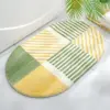 Ovaler Badteppich mit grün-gelbem Streifenmuster, ideal für moderne Badezimmer.
