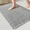 Grauer, umgefalteter Badteppich mit Fransen und Struktur, ideal fürs Badezimmer.