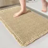 Umgefalteter Badteppich mit Fransen und Waffelstruktur, beige, für Badezimmer.