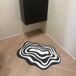 Geschwungene Badematte in Schwarz-Weiss auf Holzboden
